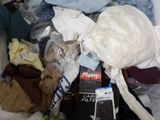 a pile of clothes and a cell phone on a bed