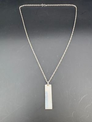 un collier en argent avec un pendentif rectangulaire monté sur une chaîne