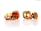 pair of gold tone cufflinks with multi colored stones on a white surface