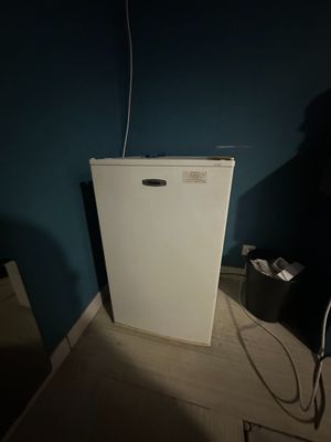 a small white refrigerator in the corner of a room