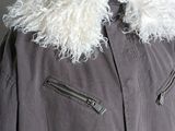 grey jacket with white fur collar and zippers on a hanger