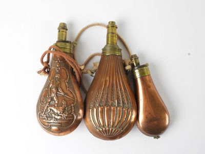 three antique brass bottle ornaments hanging from a rope on a white surface