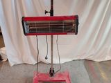 un radiateur rouge posé sur un pied devant un fond blanc