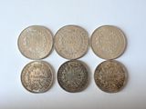 six different types of coins sitting on top of a white surface