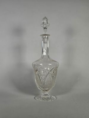 une carafe ancienne en cristal taillé, ornée d'un oiseau sur le bouchon