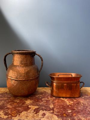 une grande marmite en cuivre et une petite marmite en cuivre posées sur une table