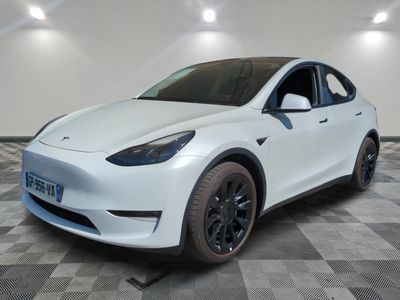 La Tesla Model Y blanche est garée dans une pièce au sol à carreaux.