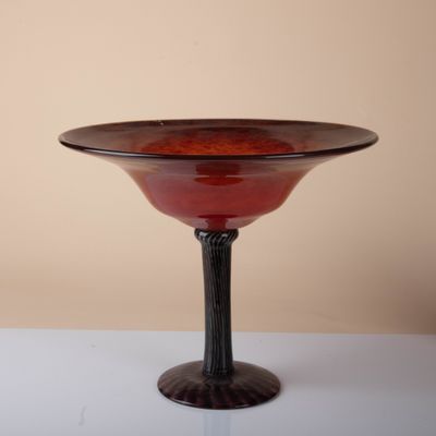 a red glass bowl sitting on top of a white table