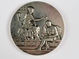 une médaille d'argent représentant un homme et une femme assis à une table