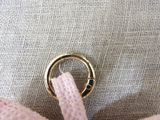 a pink teddy bear with a gold ring on it ' s neck