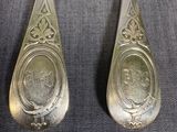 pair of silver spoons with a picture of a man and a woman on them