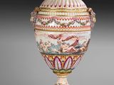 an ornately decorated vase with a lid on a pedestal