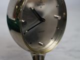 une horloge en argent posée sur une table en marbre