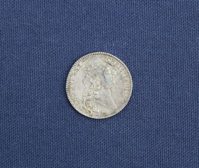 un gros plan d'une pièce d'argent posée sur un tissu bleu