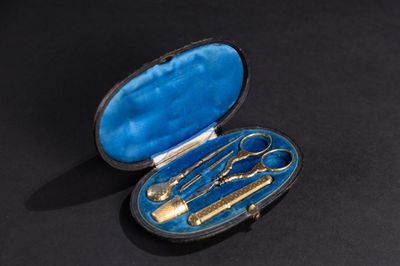 une boîte bleue contenant des cuillères dorées et une paire de ciseaux