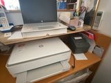 a laptop computer sitting on top of a printer on a desk