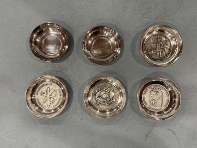 six bols en métal argenté, ornés de motifs différents, posés sur une table