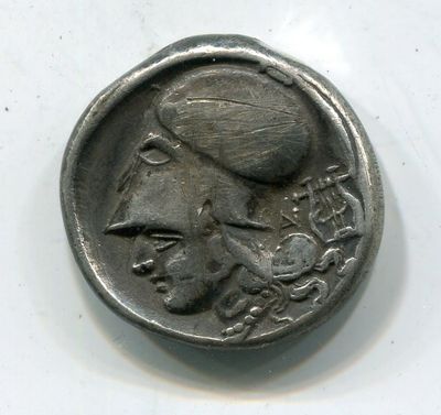 une vieille pièce de monnaie sur laquelle figure un oiseau, posée sur une surface blanche