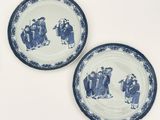 two blue and white plates with a painting of people on them