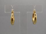 une paire de boucles d'oreilles plaquées or exposées dans une vitrine