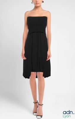 femme en robe noire posant pour une photo devant un fond blanc