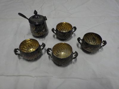 six silver plated teapots and cups with spoons on a white cloth