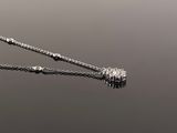 a close up of a diamond necklace on a chain on a reflective surface