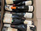 several bottles of wine are in a cardboard box on a tile floor