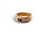 gros plan d'une bague en or avec une pierre en saphir