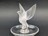une figurine d'oiseau en verre transparent posée sur une assiette en verre