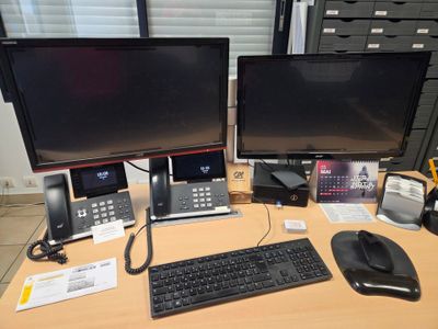 deux écrans d'ordinateur et un clavier posés sur le bureau