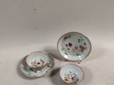 three pieces of porcelain tea cups and saucers on a white surface