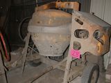 a cement mixer sitting in a garage next to a pile of pallets