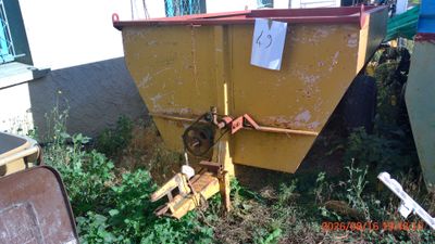 a yellow dumpster sitting in the grass next to a building