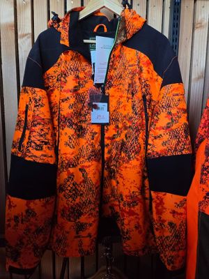 an orange and black jacket hanging on a rack in front of a wooden wall
