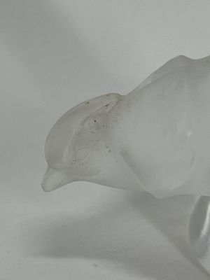 a glass bird that is sitting on a white surface