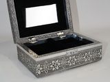 une boîte en argent contenant un miroir, posée sur une table