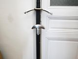 une épée posée par terre devant une porte
