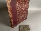 un vieux livre posé à côté d'un petit livre sur une table