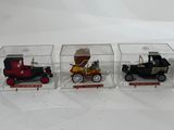 three small toy cars in a clear box on a white surface