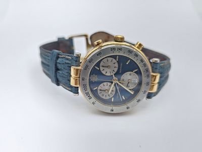 une photo d'une montre posée sur une surface blanche, avec un bracelet bleu