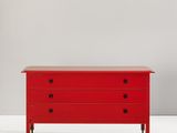 une commode rouge posée contre un mur blanc