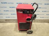 a red machine sitting on top of a cement floor next to a wall