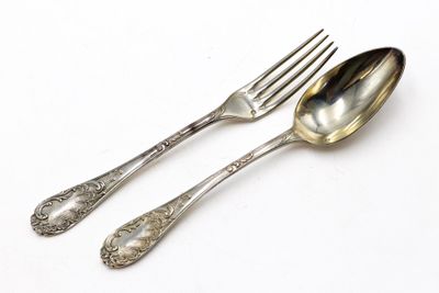 deux cuillères et une fourchette en argent sur une surface blanche