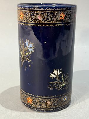 un vase bleu orné de motifs dorés et de fleurs