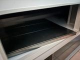an open oven with a black tray inside of it