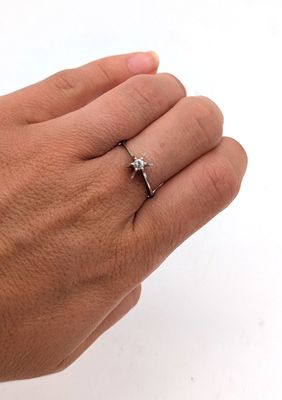 la main d'une personne tenant une bague sertie d'un diamant