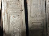 trois vieilles portes posées dans une pièce, près d'un mur de briques
