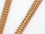 a close up of a gold chain on a white surface