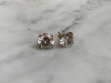 a pair of diamond stud earrings on a marble surface